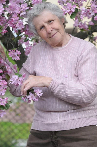 Счастливая бабушка на фоне розовых цветов — стоковое фото
