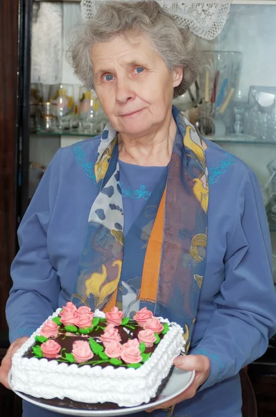 Zeventig jaar oude vrouw houd taart — Stockfoto