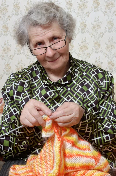 Spectacled grandmother binds cardigan — Stock Photo, Image