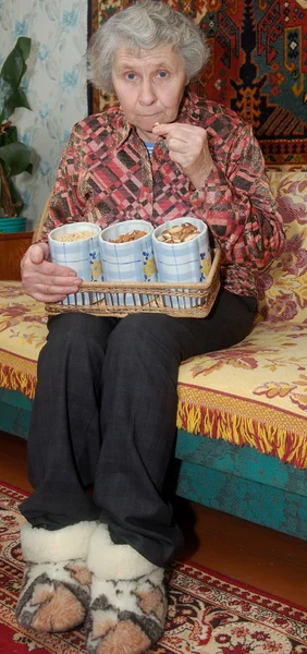 Sjuttio år gammal kvinna knäcker nötter — Stockfoto