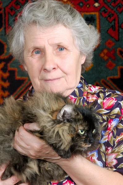 Mormor sitter med katt på hennes händer — Stockfoto