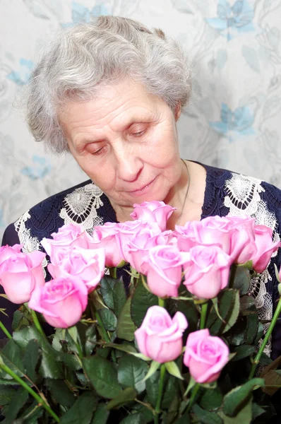 Portrét babičky za kyticí růžové růže — Stock fotografie
