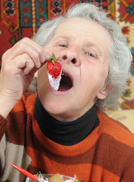 祖母は熟したイチゴを食べる — ストック写真