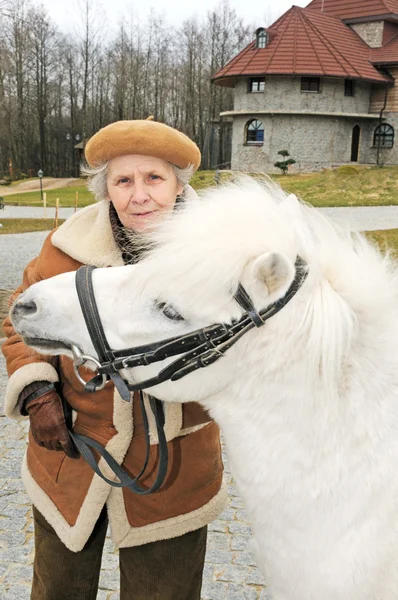 Happy grandmother with white pony — Stock Photo, Image