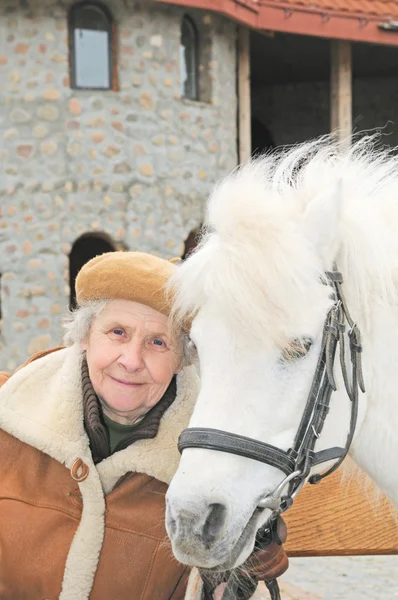 Пожилая женщина рядом с пони — стоковое фото