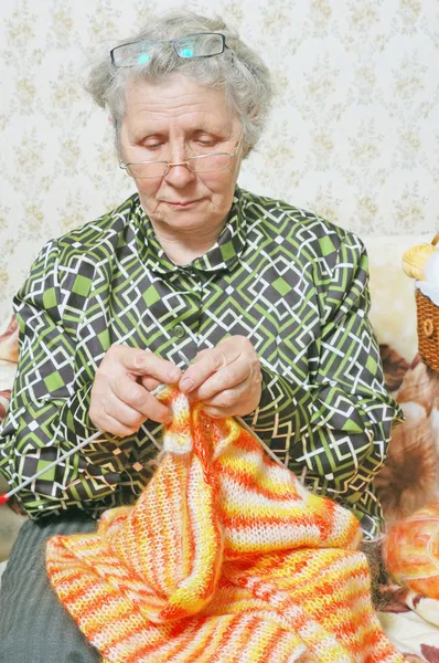 Gözlüklü yaşlı kadın hırka bağlar — Stok fotoğraf