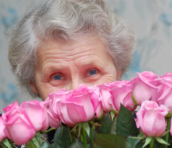 奶奶背后的粉红色的玫瑰花束 — 图库照片