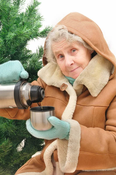 Granny met hete thee onder spar — Stockfoto