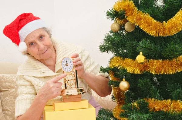 Oma in rode Kerstman hoed en klok — Stockfoto
