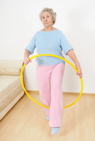 Starší dáma dělá gymnastiku s hula-hoop — Stock fotografie