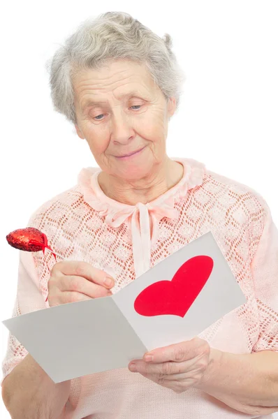 Femme âgée tenir carte postale avec la forme du cœur sur elle couverture — Photo