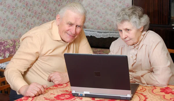 Vieux couple regarder à l'ordinateur portable avec un intérêt actif — Photo