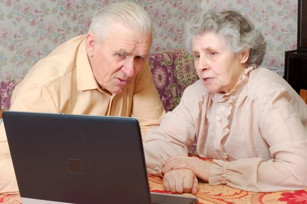 Пожилая пара смотреть на ноутбук с активным интересом — стоковое фото