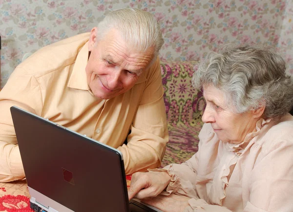 Пожилая пара смотреть на ноутбук с активным интересом — стоковое фото