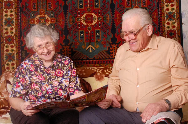 年配のカップルを読むニュースと笑顔 — ストック写真