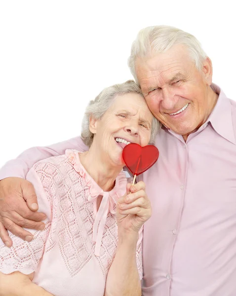 Lächelndes altes Paar mit roten herzförmigen Süßigkeiten — Stockfoto