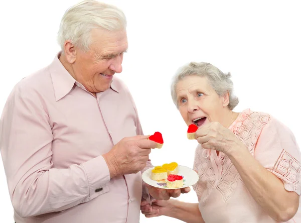 Happy old couple with red and yellow heart-shaped cookies — Stock Photo, Image