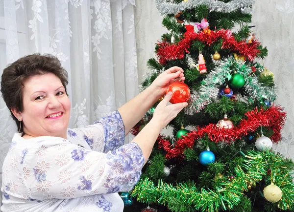 Elderly woman decorates Christmas tree — Stock Photo, Image