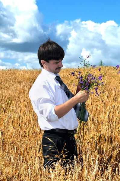 Businessman picks flowers fron field — Stock Photo, Image