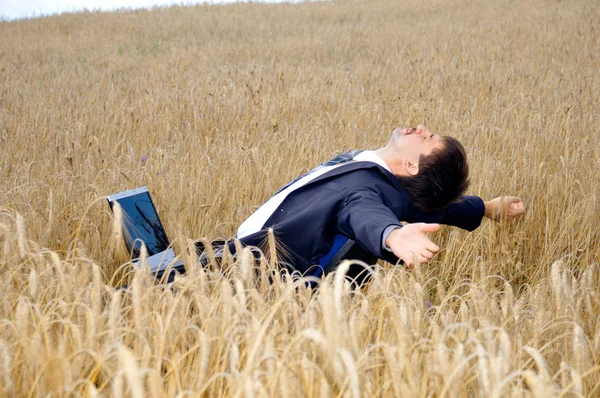 Young businessman takes a rest in field — Stock Photo, Image