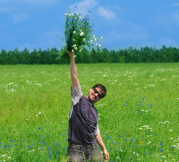Happy young adult man with bouquet of wildflowers — Stock Photo, Image