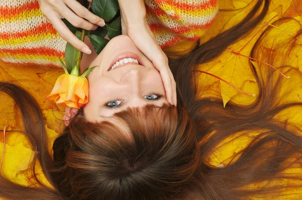 Girl lies on heap of yellow leaves — Stock Photo, Image