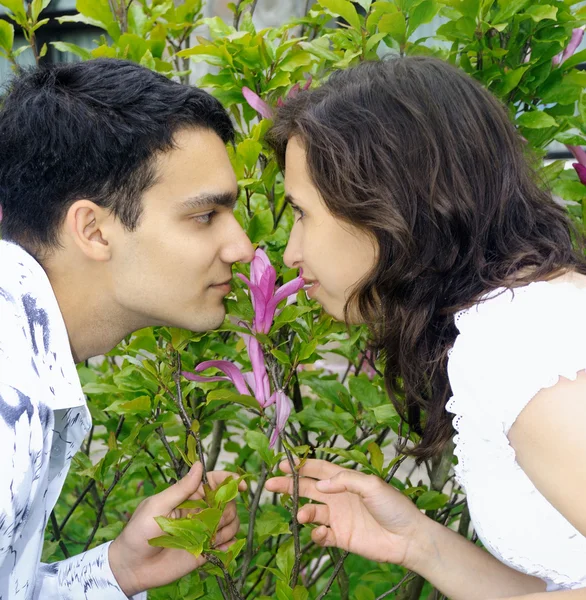 Beautiful young couple outdoors smells a flower — Stock Photo, Image