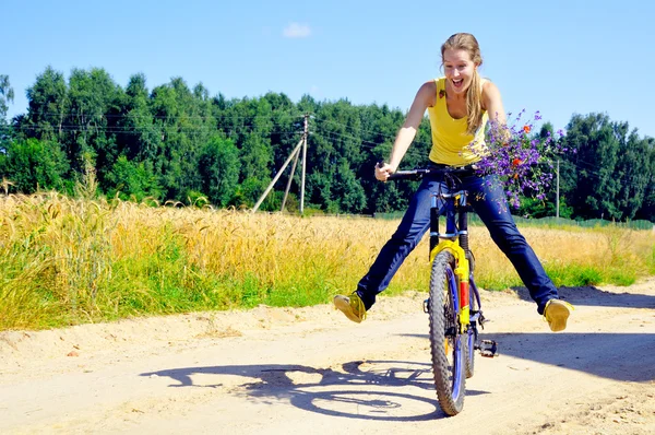 Hermosa chica sonriente paseos en bicicleta en el camino del pueblo —  Fotos de Stock