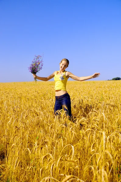 Beautiful girl jumps in golden field — Stock Photo, Image