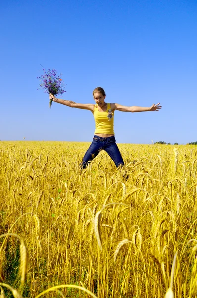 Beautiful smiling girl jumps in golden field — Stock Photo, Image