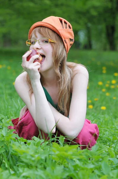 Glückliches junges Mädchen mit Brille isst einen Apfel — Stockfoto