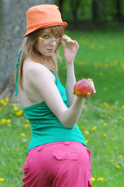 Νεαρό κορίτσι διοπροφόρος και στο καπό με μήλο — Φωτογραφία Αρχείου