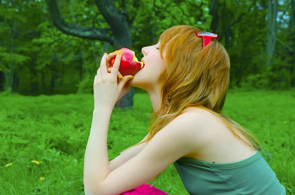 Девочка кусает яблоко — стоковое фото