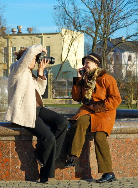 stock image Adult daughter takes photo of her mother talking on mobile