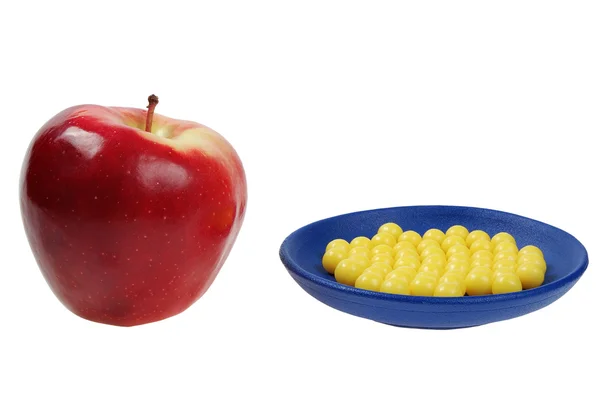 Голубая пластинка из желтых капель витамина и красного яблока — стоковое фото
