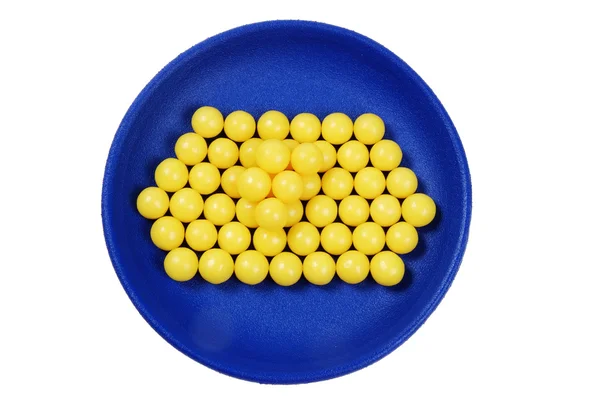 Blue plateful of yellow drops vitamin — Stock Photo, Image