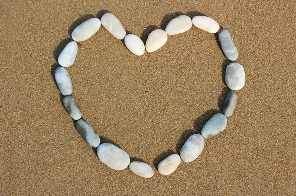 Coração de seixos em areia — Fotografia de Stock