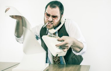 Irate chief at desk holding rotary phone in anger reading over fax clipart