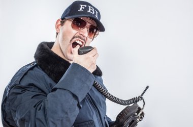 Irate FBI agent wearing blue jacket, yelling on radio clipart