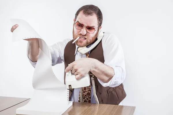 Irate professional at desk holding rotary phone reading fax — Stock Photo, Image