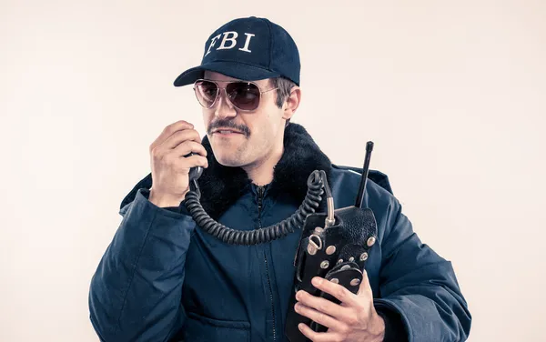 Agent en colère du FBI en veste anti-émeute sur le point de jurer sur la radio vintage Image En Vente