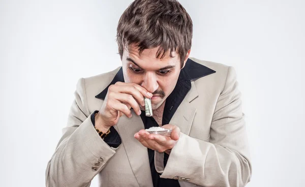 Loco joven hombre de negocios haciendo cocaína con billete de dólar en traje Imagen de archivo