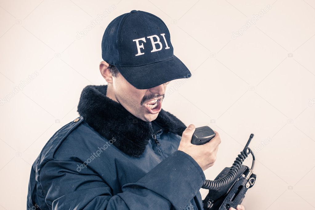 Furious FBI man bearing teeth under cap, blue jacket on vintage radio