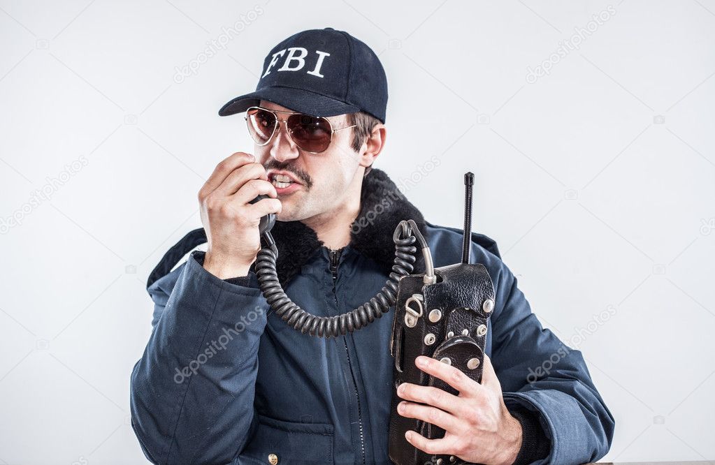 Young white FBI agent commading others on the radio