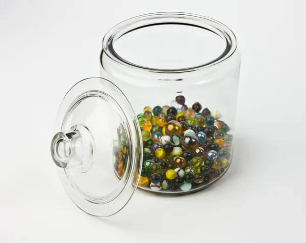 Tarro de vidrio medio lleno de coloridos mármoles de vidrio — Foto de Stock