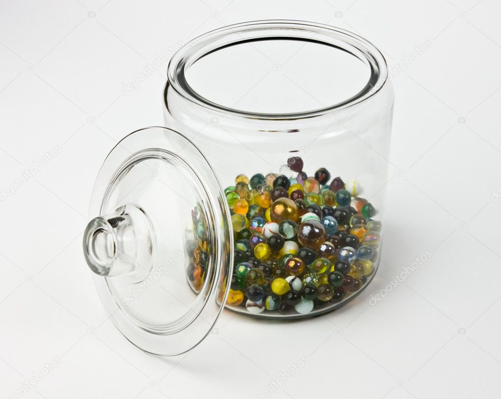 Glass jar half full of colorful glass marbles