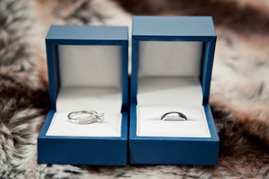 Two Blue Boxes Containing wedding rings on textured table clipart