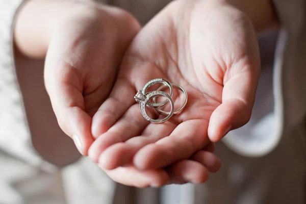 Vue rapprochée de deux mains tenant trois anneaux de mariage Photos De Stock Libres De Droits