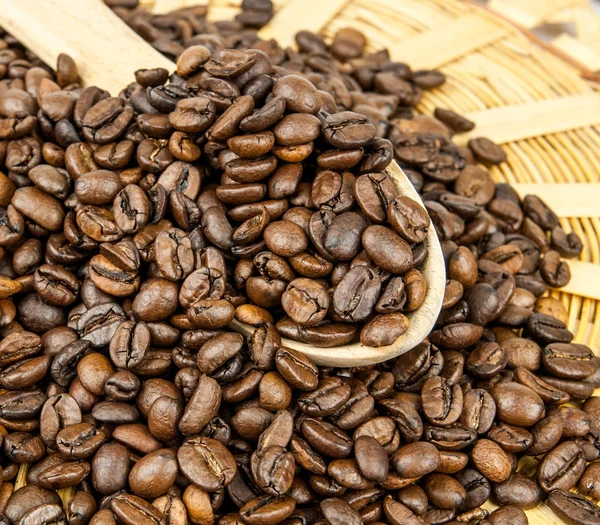Kávová zrna v dřevěnou lžící a jako pozadí. — Stock fotografie