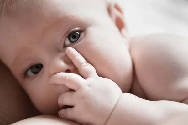 Bebé se acuesta en el pecho de su madre y cierra su cara de palma — Foto de Stock